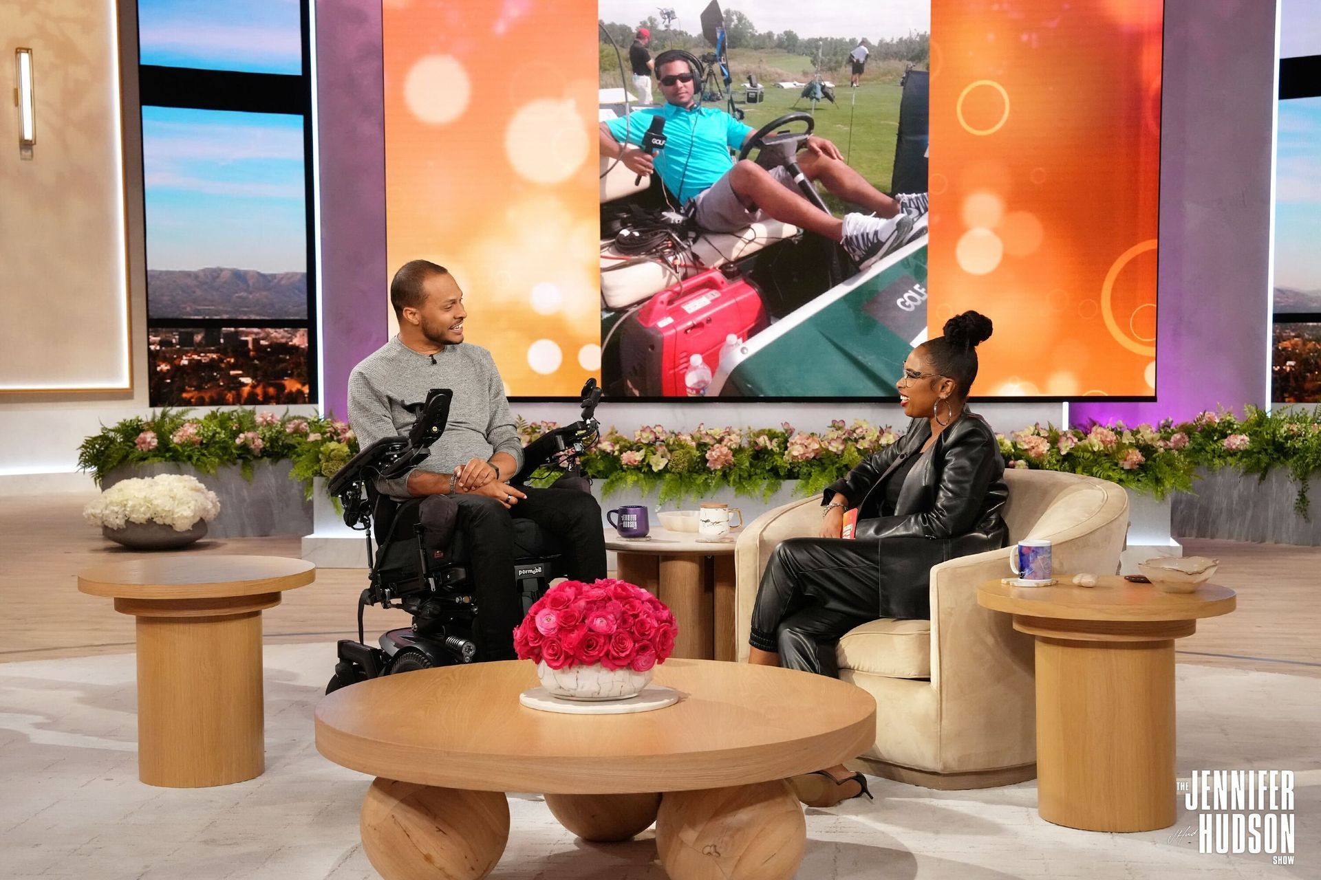 A man in a wheelchair is sitting next to a woman in a chair on a talk show.