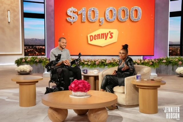 A man in a wheelchair sits next to a woman in a chair in front of a denny 's sign