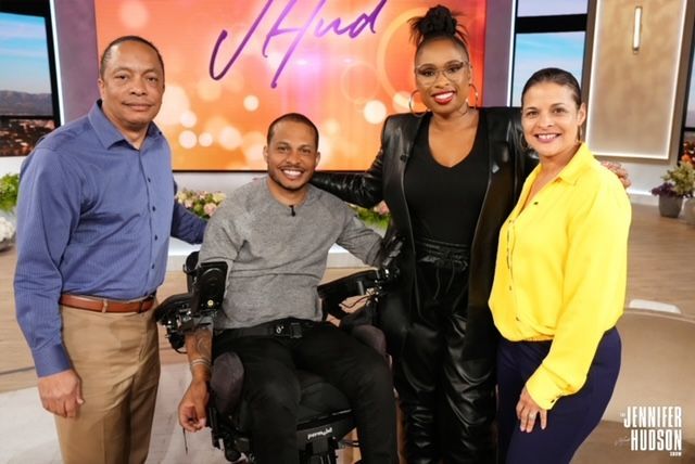 A man in a wheelchair is posing for a picture with two other people