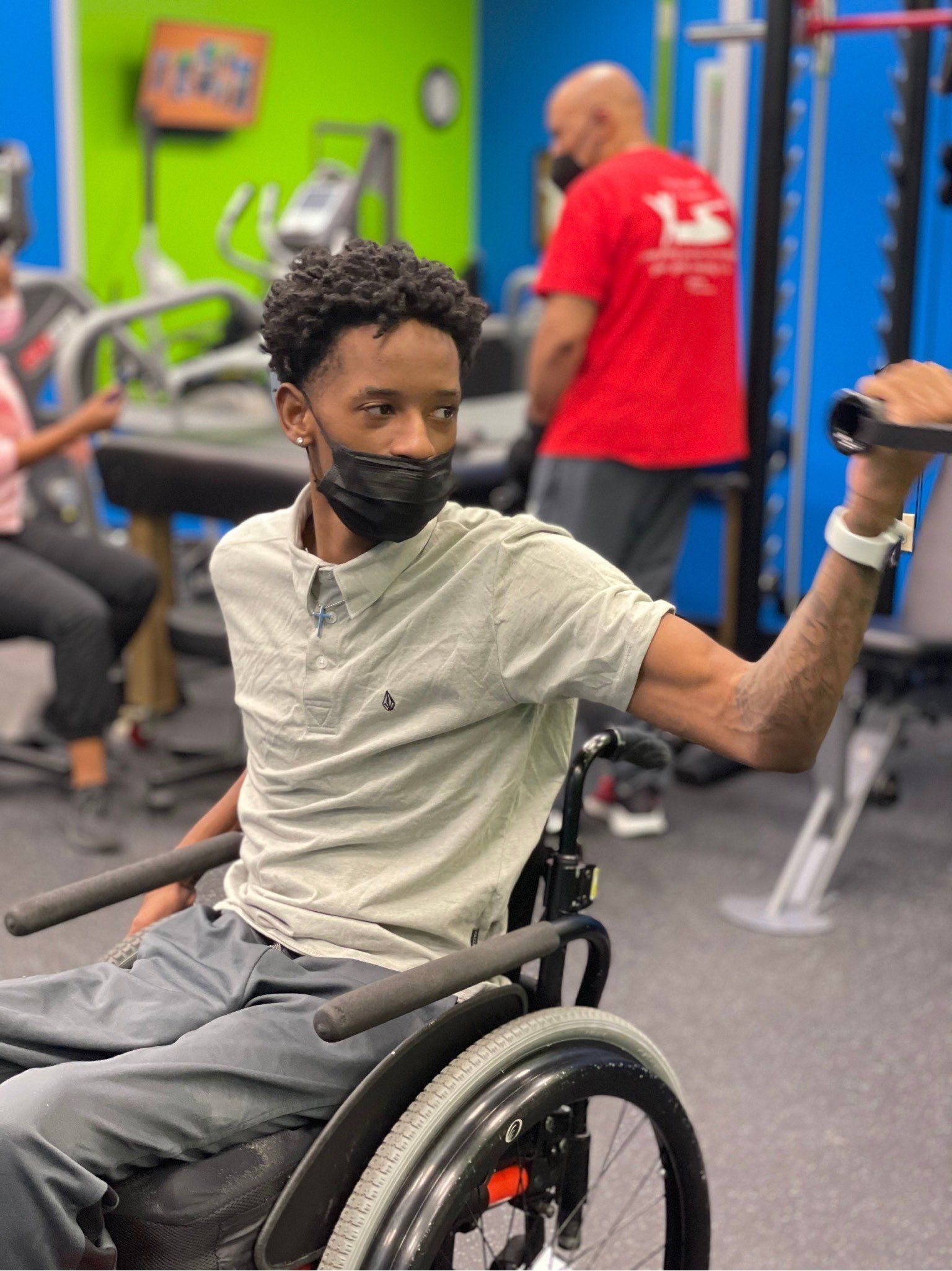 A man in a wheelchair is lifting weights in a gym