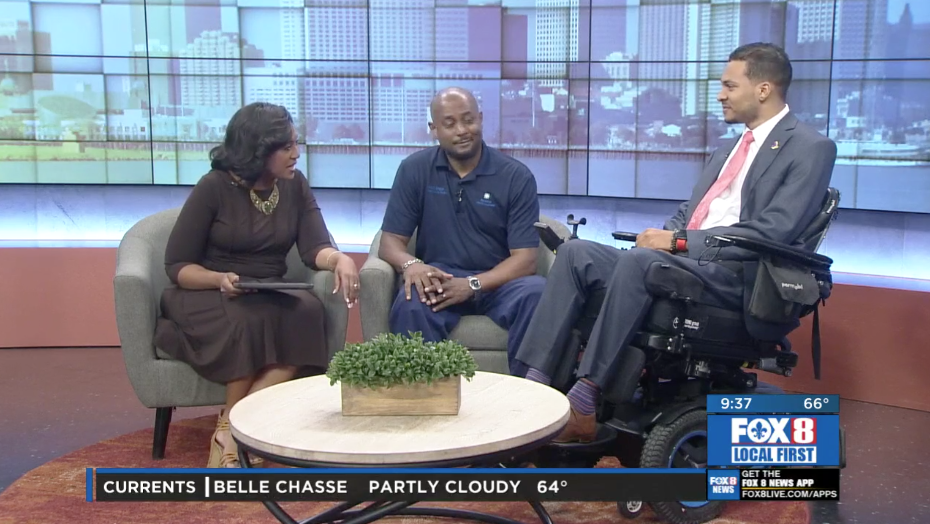 A man in a wheelchair is talking to a woman and a man in a suit.