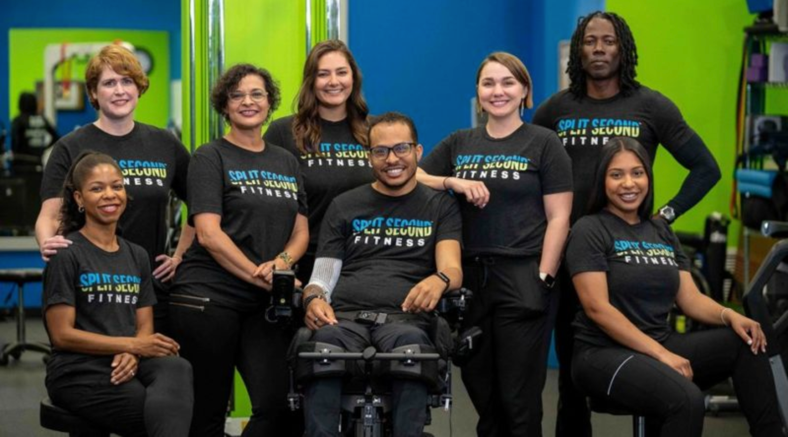 A group of people are posing for a picture in a gym.