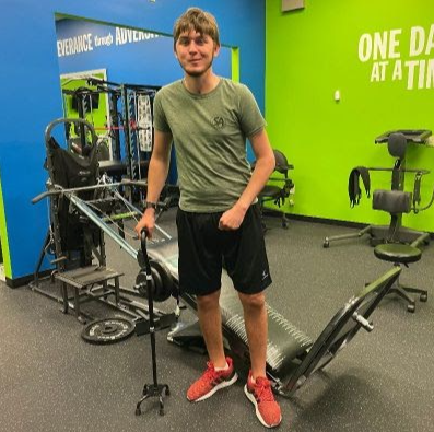 A man in a gym with a sign that says one day at a time