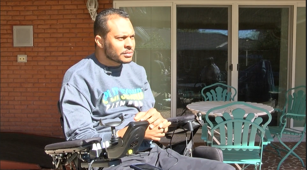 A man in a blue shirt is sitting in a wheelchair