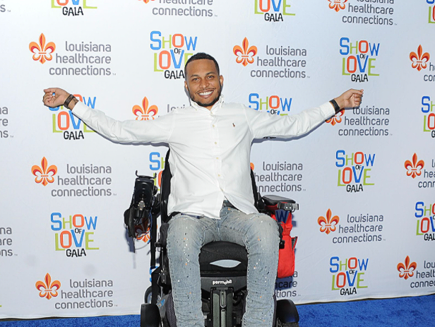 A man in a wheelchair is standing in front of a wall that says show love