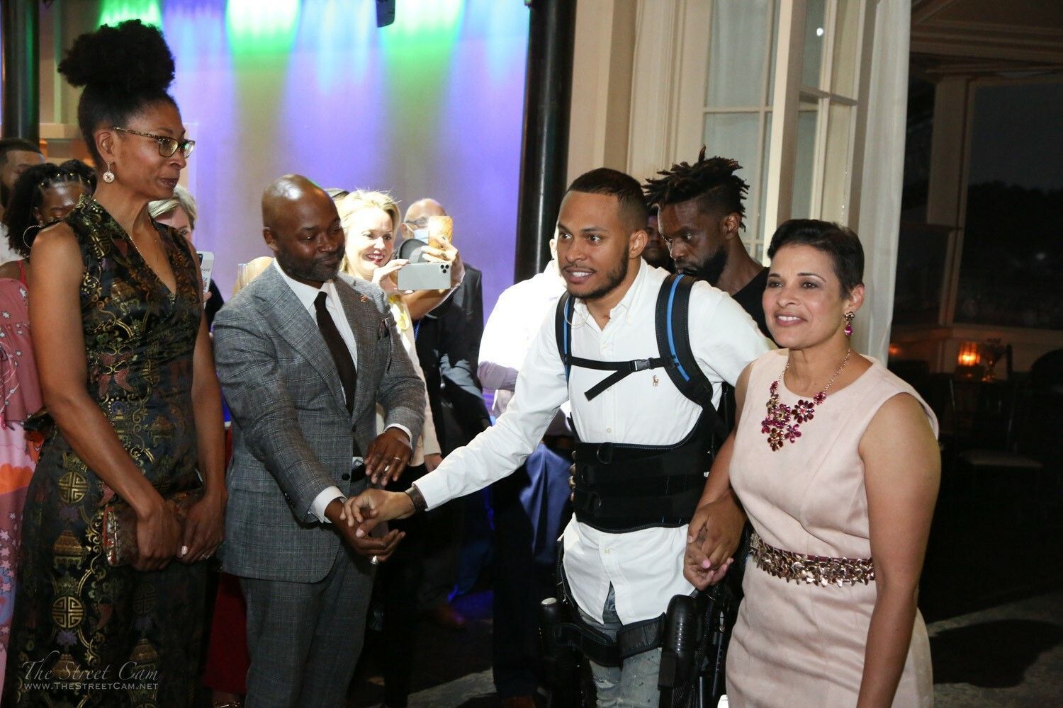 A group of people are standing around a man wearing a backpack