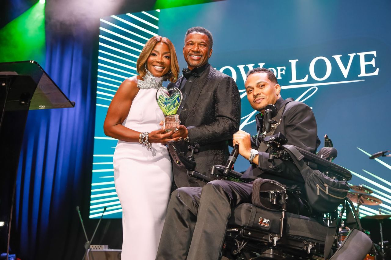 Gala chairs Ryan and Stephanie Burks hold their Show of Love award on stage with Mark Raymond Jr.