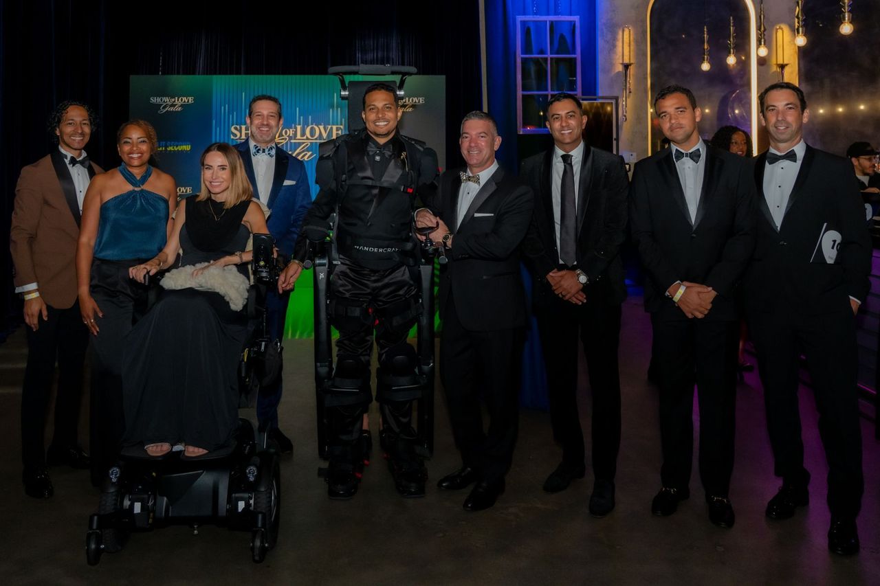 Mark Raymond Jr., standing in an exoskeleton, poses with a group of gala guests.