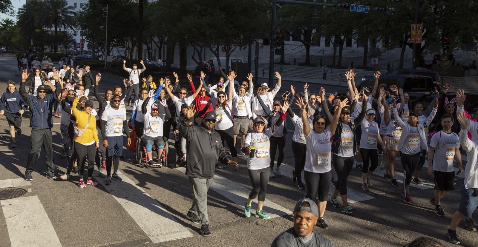 Dozens of Team Split Second runners, walkers and wheelchair users wave from St. Charles Avenue during the Crescent City Classic