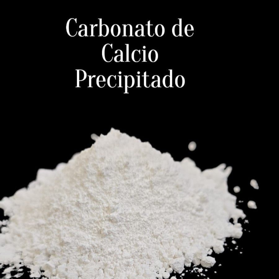 Montón de carbonato de calcio precipitado blanco en polvo sobre fondo negro con etiqueta en español.