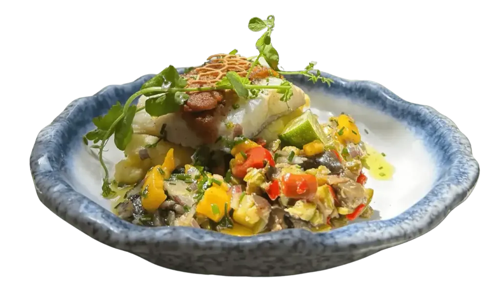 Un filet de poisson blanc servi sur un sauté de légumes colorés dans un bol en céramique texturée à bord bleu.