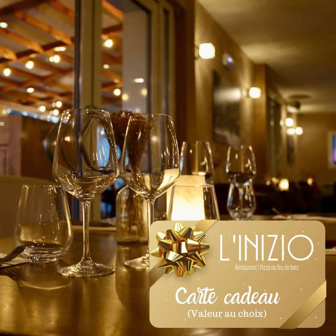 Une carte-cadeau pour le restaurant « L'INIZIO » est superposée à l'image d'une table de restaurant élégante, faiblement éclairée, avec des verres à vin.