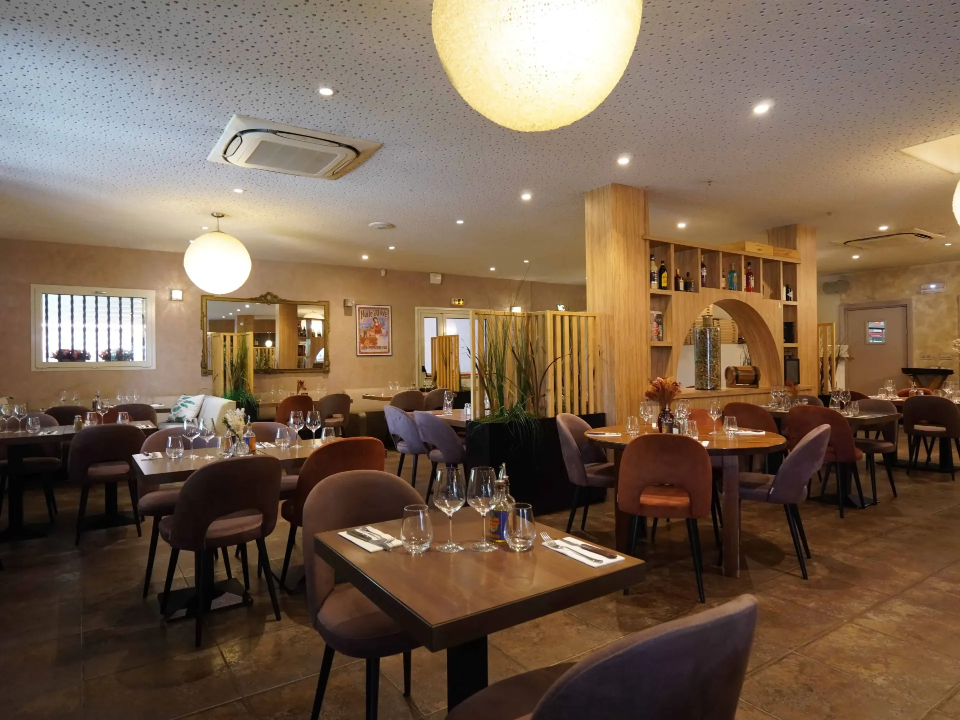 Un intérieur de restaurant moderne avec des tables et des chaises, des éléments en bois et un éclairage suspendu chaleureux.