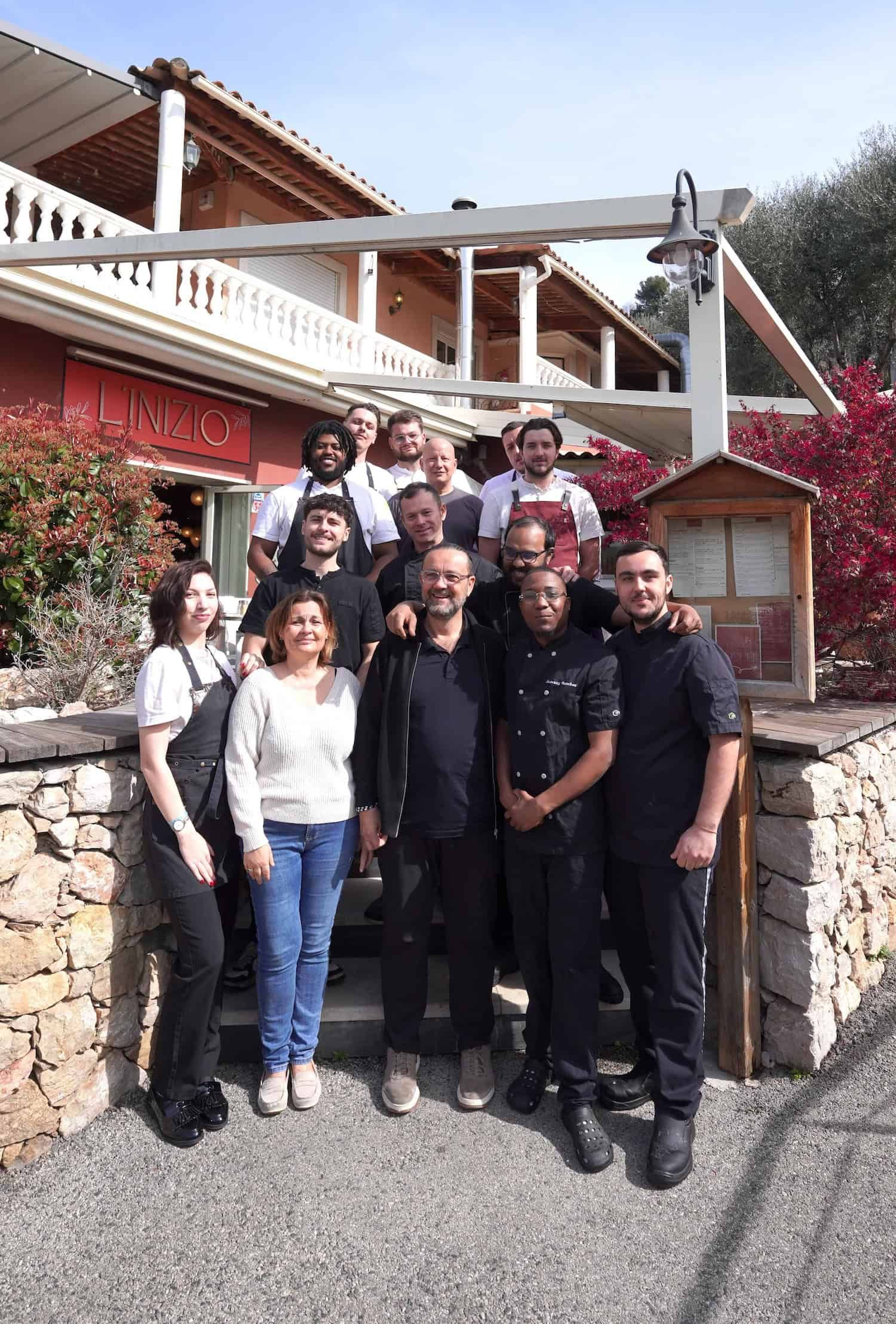 Un groupe d'employés de restaurant pose pour une photo devant leur établissement.