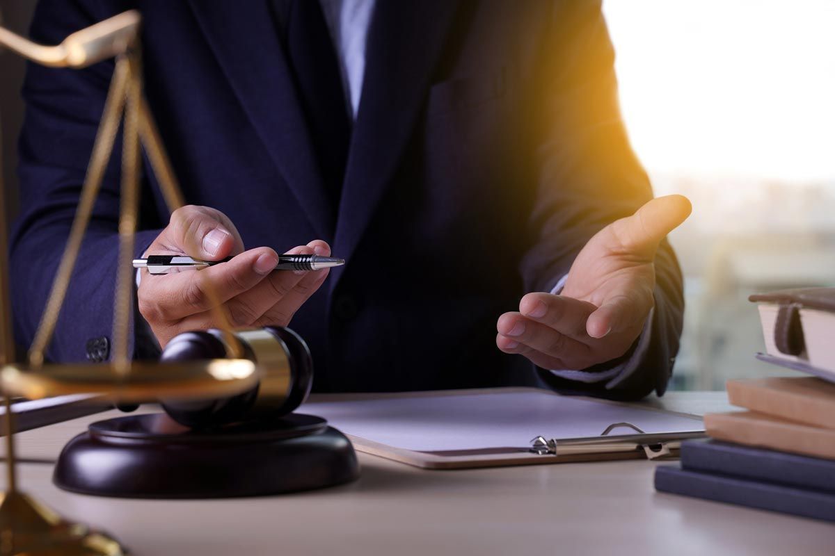 A lawyer is sitting at a desk holding a pen and a cell phone.