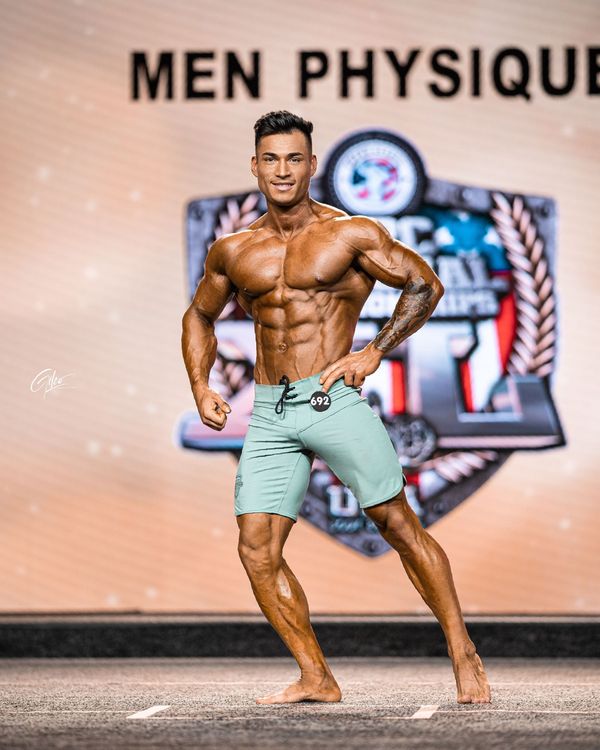 A shirtless man is holding two dumbbells in his hands.