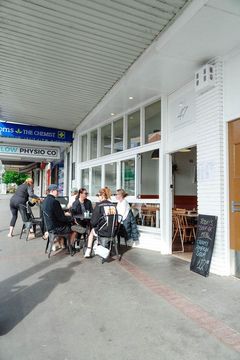 A group of people are sitting at tables outside of a restaurant.