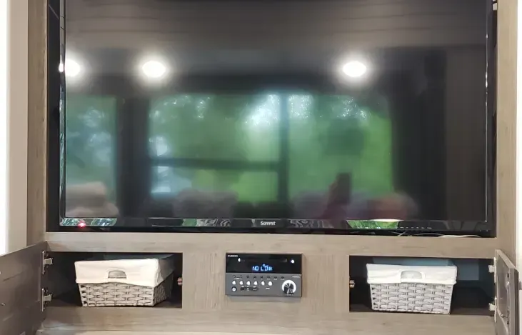 a large flat screen tv is sitting on top of a wooden entertainment center .