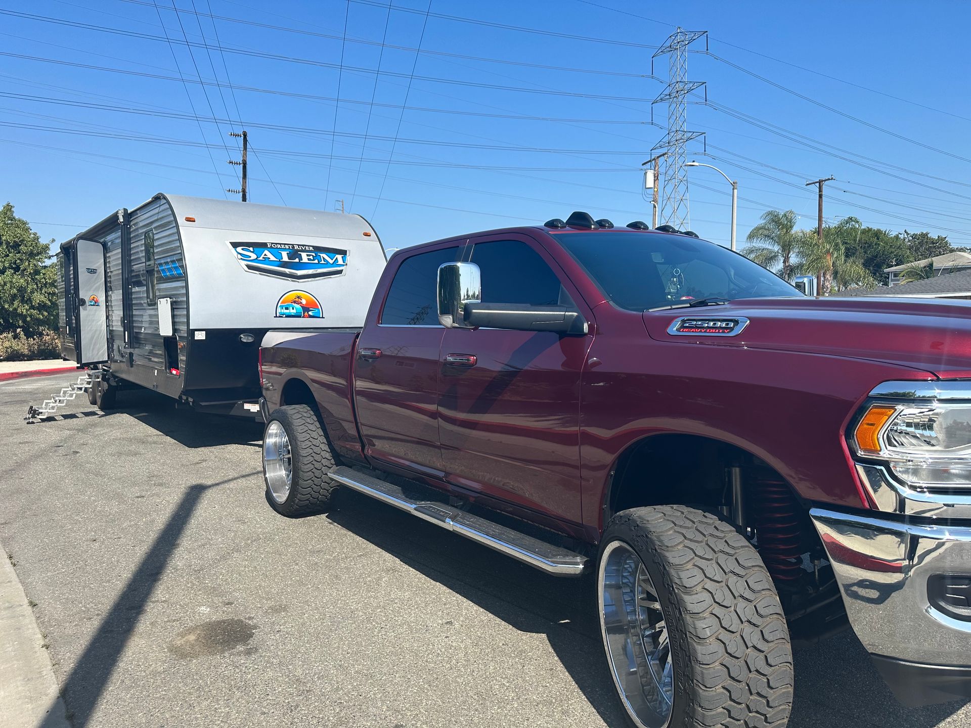 a red truck is towing a trailer in a parking lot .