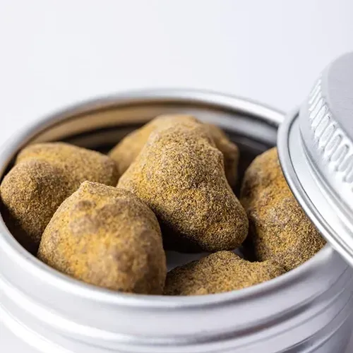 Open tin filled with cannabis moon rocks, light brown with gold dusting.