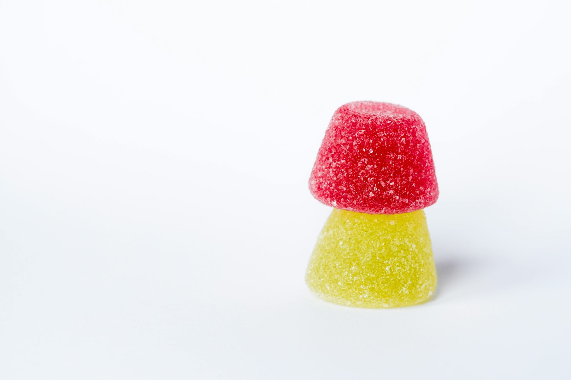 Two stacked gumdrop candies, red top, yellow base, on white background.