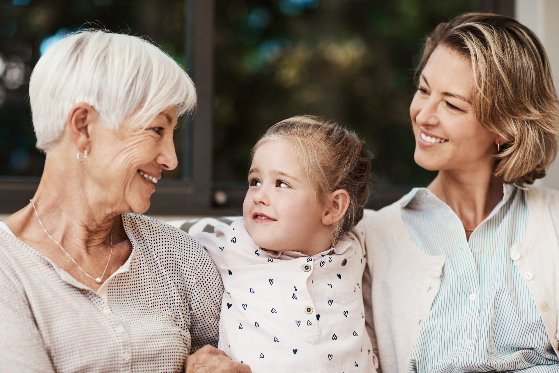 Three people smiling outdoors, with a young child between two adults.