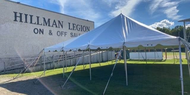 A white tent is sitting in front of a hillman legion building