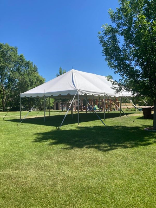 A large white tent is sitting in the middle of a grassy field.