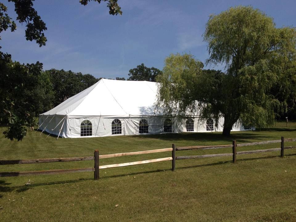 A large white tent is in the middle of a grassy field