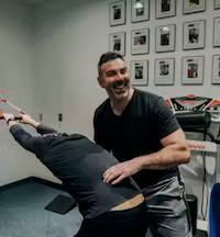 a person stretching someone's back and smiling