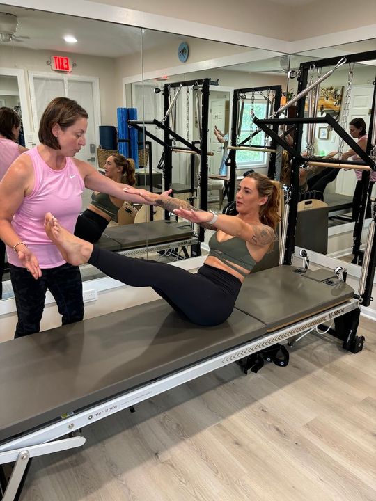 Pilates and Intuitive Energy Healing. Asha is doing pilates on a pilates machine in a gym.