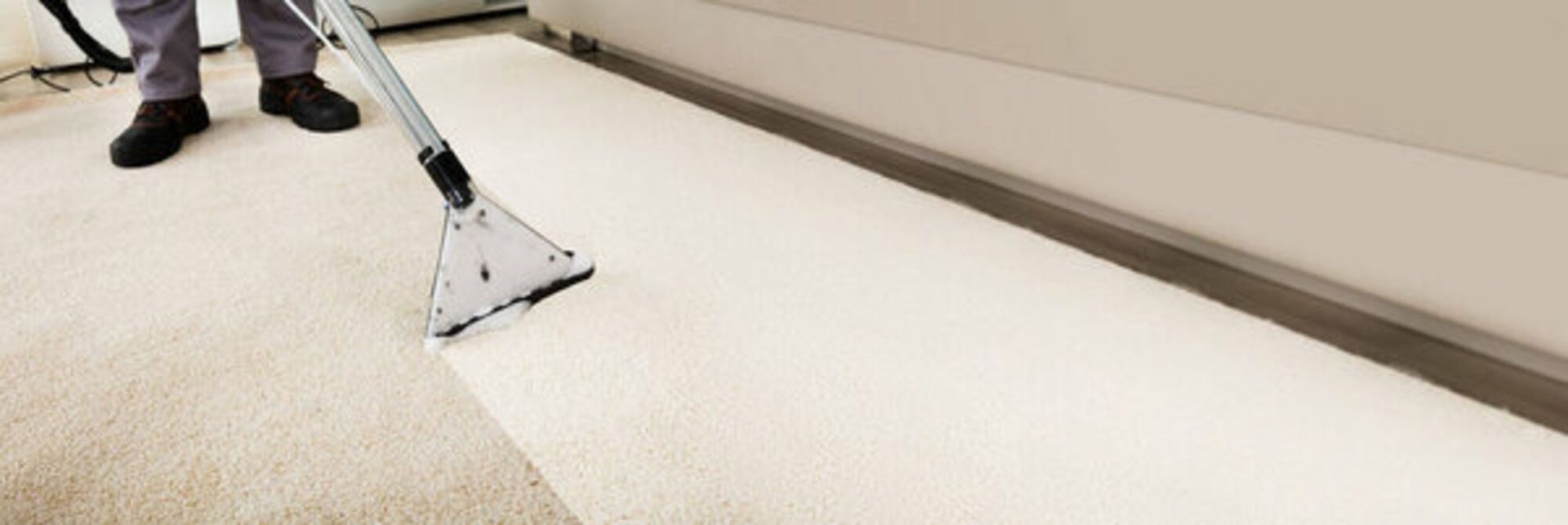 A person is cleaning a carpet with a vacuum cleaner.