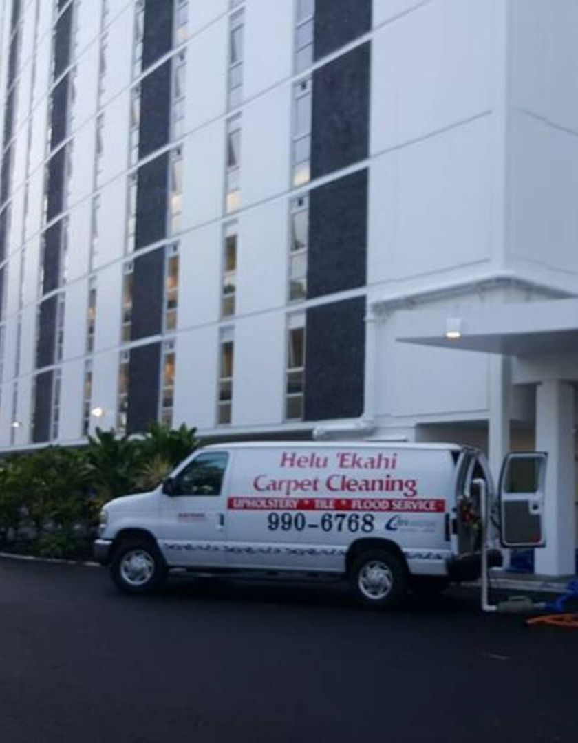 A carpet cleaning van is parked in front of a building