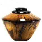 Small wooden lidded jar with dark top and a round side opening, in brown and black tones