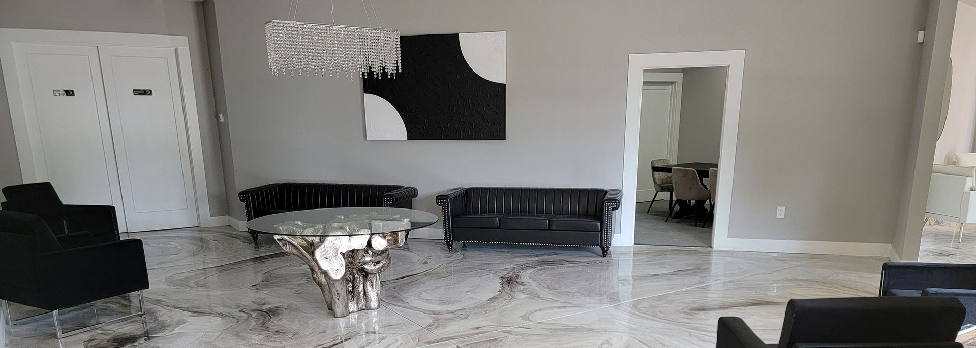 Bright living room with gray walls, black sofas, white area rug, coffee table, and open doorway