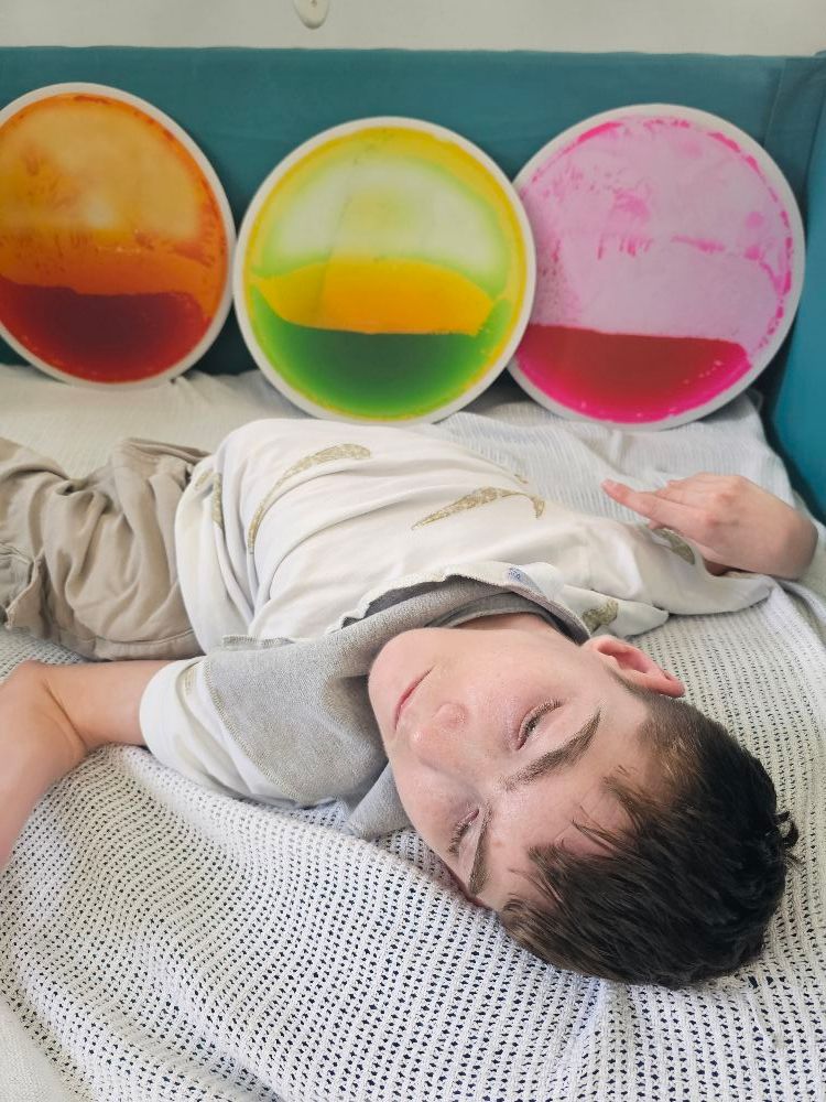 A person lying on a bed points at colorful, round liquid-filled pads.