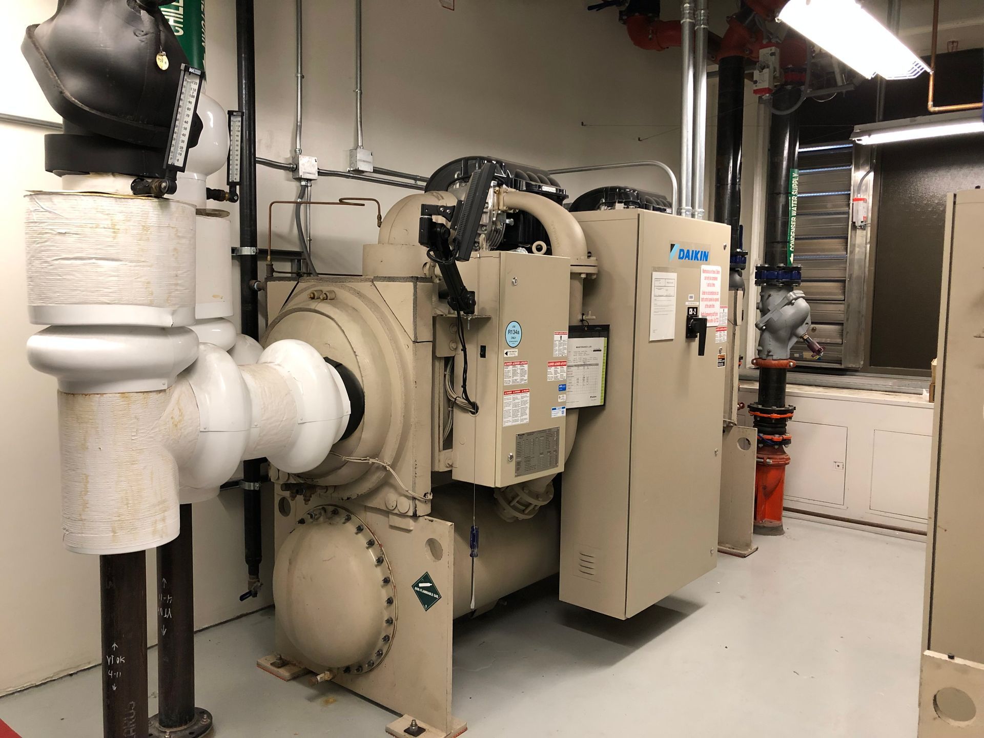 A large machine is sitting in a room with pipes.