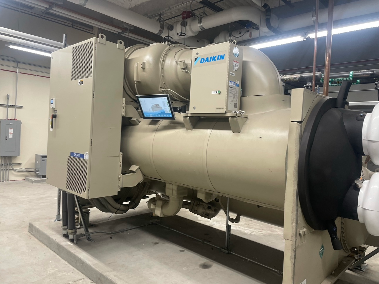 A large chiller is sitting in a room with a monitor on top of it.