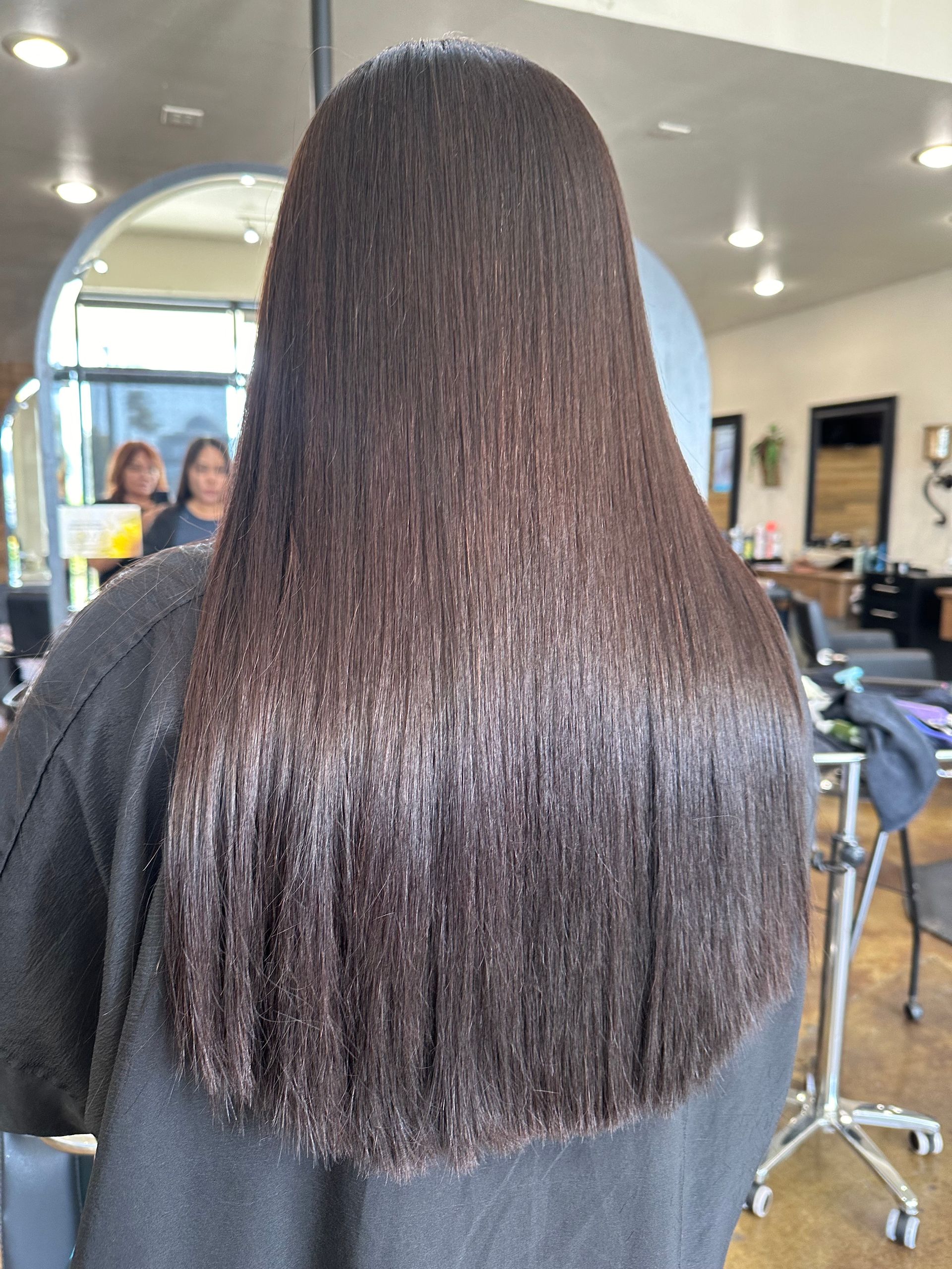 Woman with long, straight, dark brown hair in a salon.