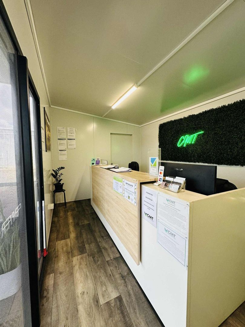 Reception area with light wood counter, artificial green wall, and small plant. — Coalfields Mechanical & Towing in Blackwater, QLD