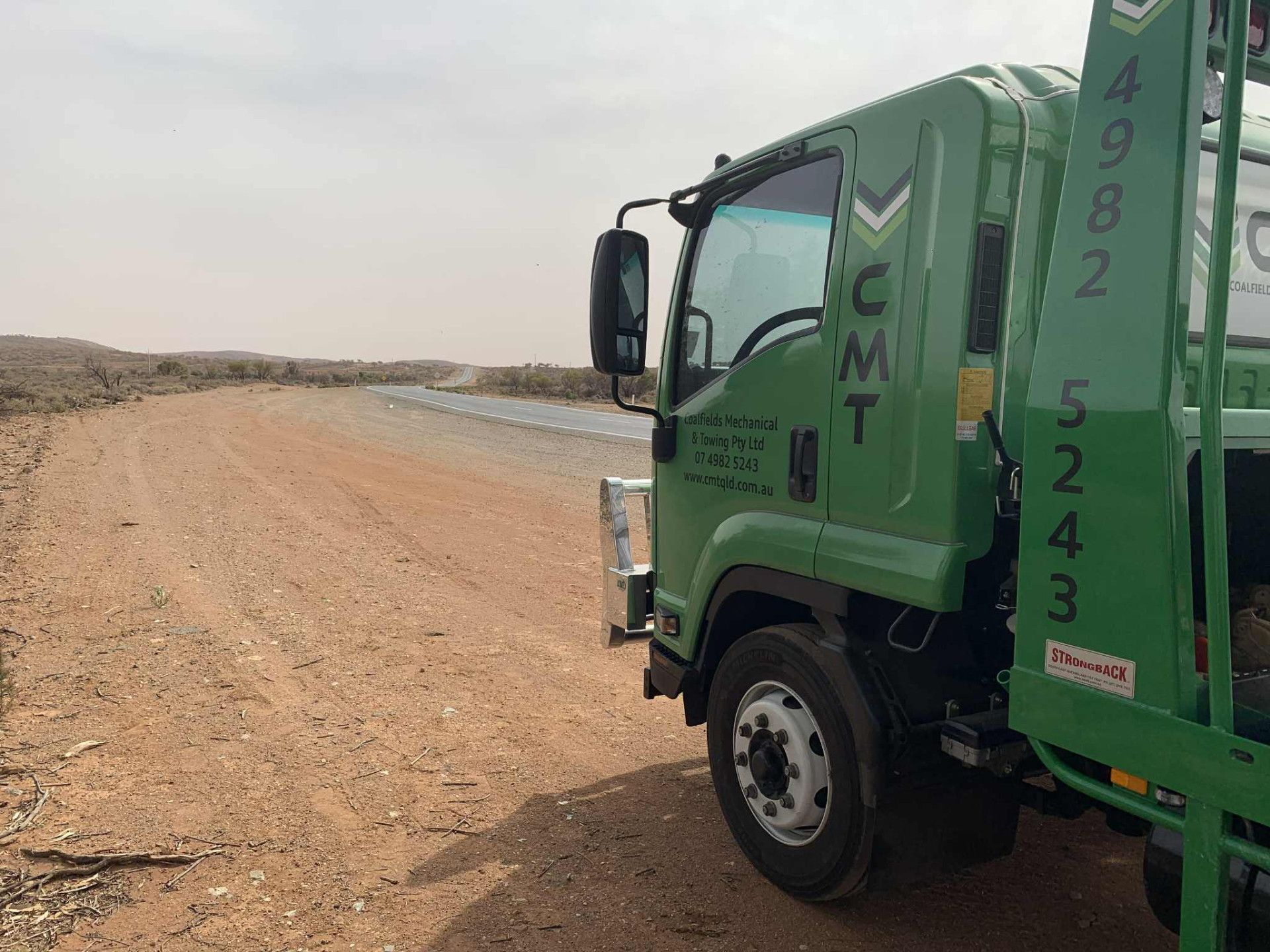 Green CMT truck on a dirt road in a dry, desert-like landscape.— Coalfields Mechanical & Towing in Blackwater, QLD