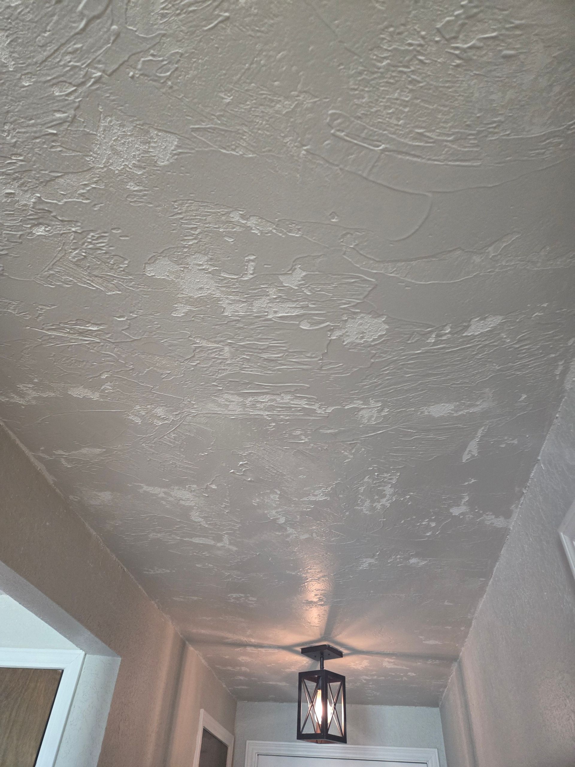 Textured white ceiling in a narrow hallway with a hanging lantern light fixture