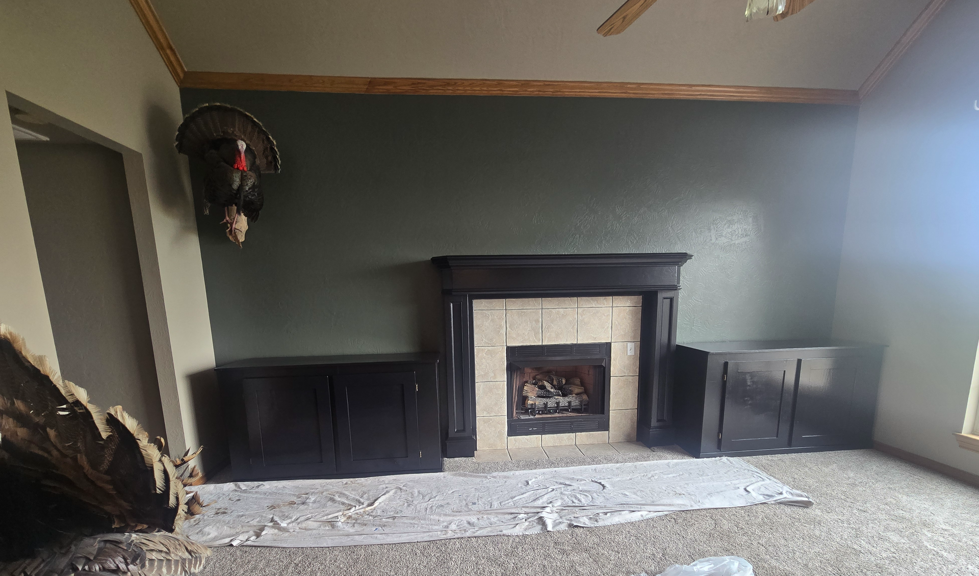 Empty living room with a dark fireplace mantel, gray walls, and carpeted floor
