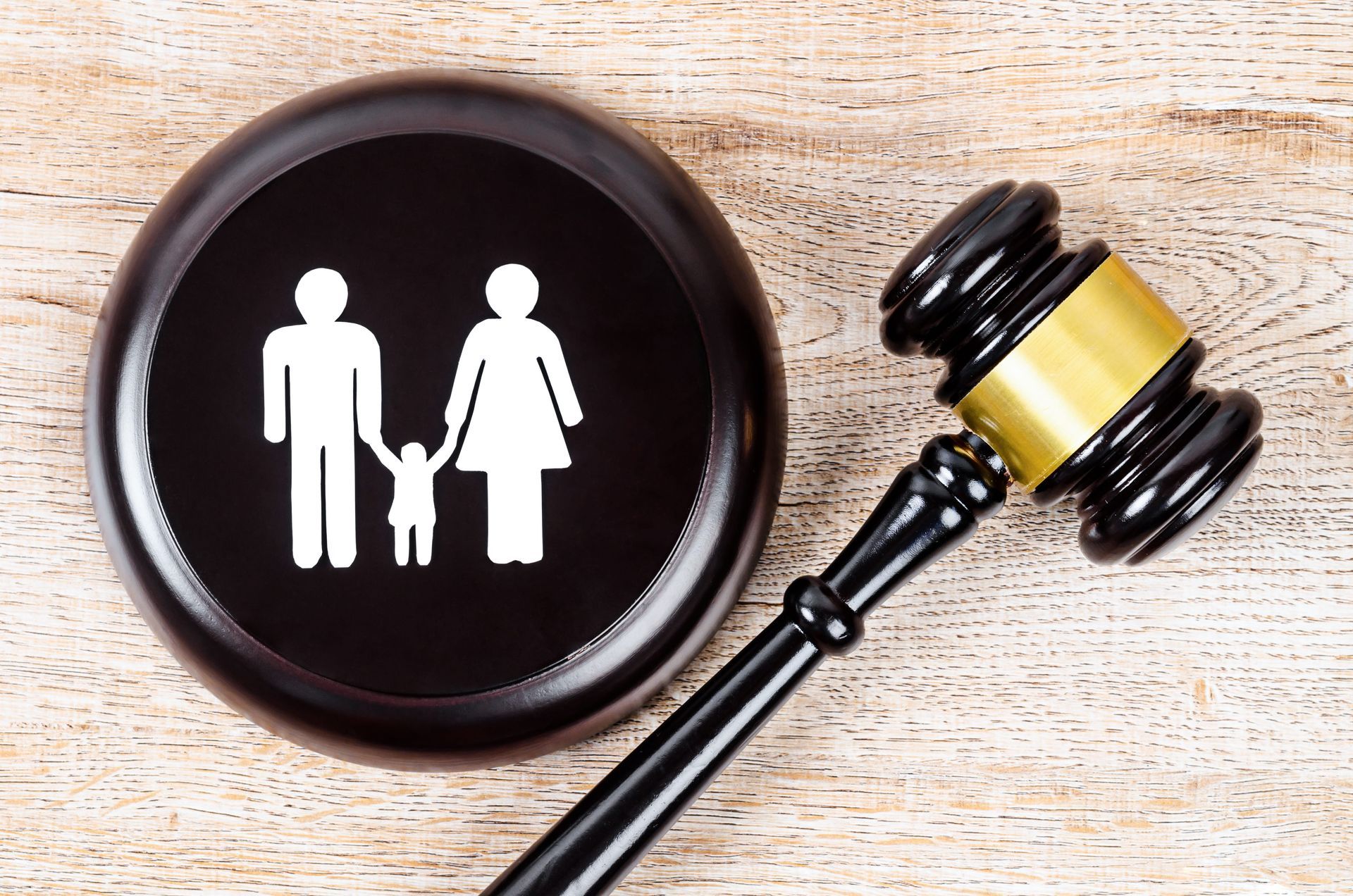Family icon on a black disk beside a judge’s gavel on a wooden surface