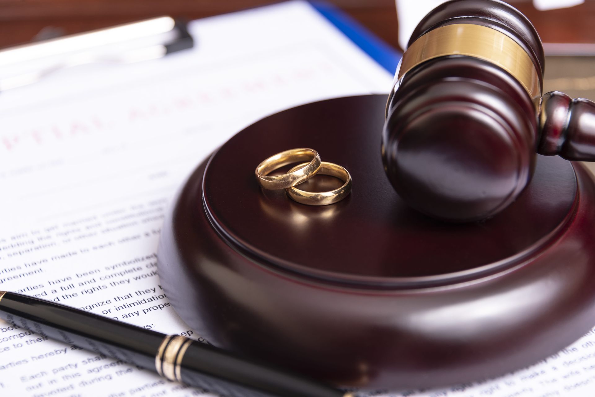 Gavel and wedding rings on a judge’s bench with legal documents in the background