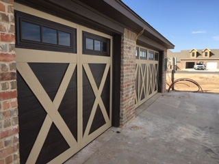 Two-car garage with brown and tan decorative doors, set in a brick and concrete setting.
