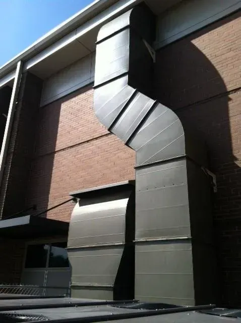 Metal HVAC ductwork against a brick building exterior.