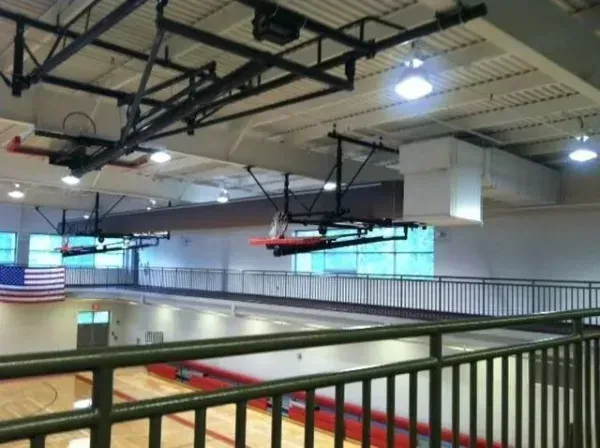 Basketball court interior with retractable hoops, viewed from an upper level.
