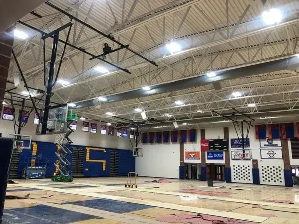 Basketball court, high school gym interior; blue and gold team colors; basketball hoops; banners and signs on wall.