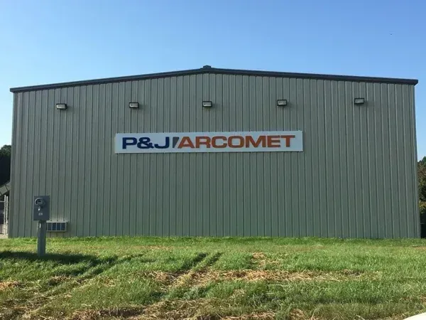 Exterior of a tan metal building with the company name